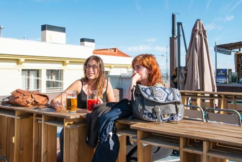 two women sitting at a picnic table with drinks at Safestay Madrid Central in Madrid