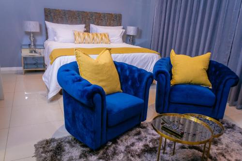 a bedroom with two blue chairs and a bed at iTowers Studio Suite in Gaborone