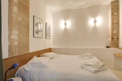 a bed in a room with two lights on the wall at Joie Paris St Germain-des-Prés - Bon Marché in Paris