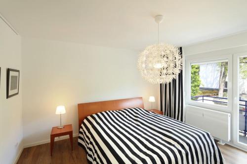 um quarto com uma cama em preto e branco e um lustre em Tanja's Ferienwohnung in Freiburg Herdern em Friburgo em Brisgóvia