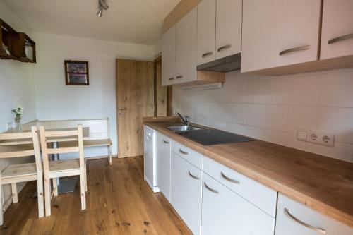a kitchen with white cabinets and a sink and a table at Innertrein in Cadipietra