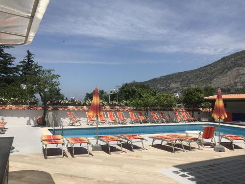 a swimming pool with chairs and umbrellas and a group at Hotel Albatros in Piano di Sorrento