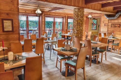 a restaurant with wooden tables and chairs and windows at Pensjonat Polonia in Krynica Morska