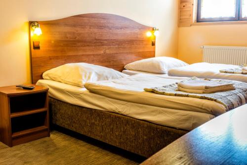 a hotel room with two beds and a wooden headboard at Bieszczadzkie Wrota Lasu in Stężnica