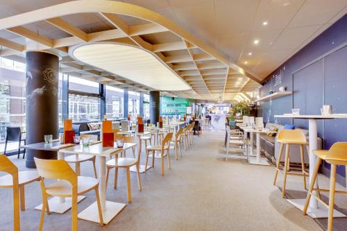 a dining area with tables and chairs in a restaurant at ibis Styles Paris Charles de Gaulle Airport in Roissy-en-France