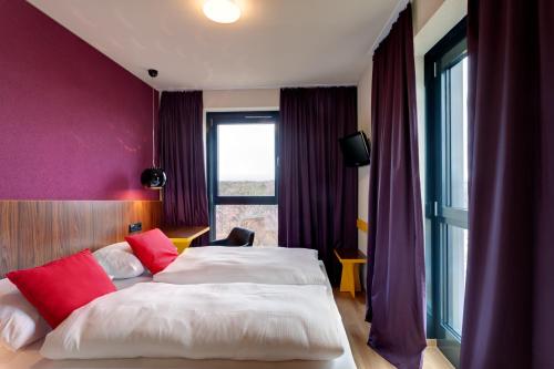 a hotel room with two beds and a window at MEININGER Hotel Frankfurt Main / Airport in Frankfurt/Main
