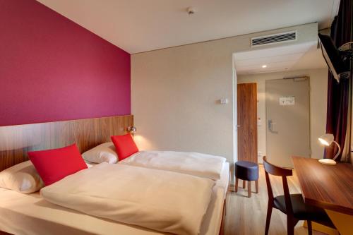 a hotel room with two beds and a table at MEININGER Hotel Frankfurt Main / Airport in Frankfurt/Main