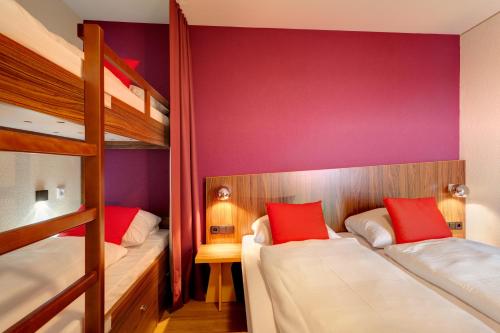 a bedroom with two bunk beds with red pillows at MEININGER Hotel Frankfurt Main / Airport in Frankfurt/Main