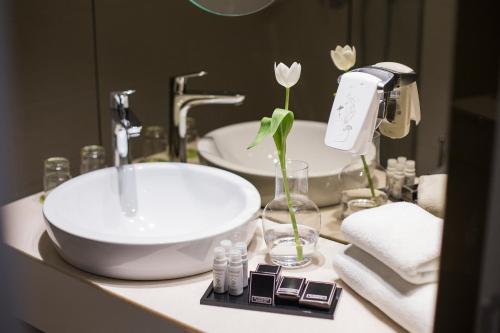 eine Badezimmertheke mit einem Waschbecken und einer Vase mit Blumen in der Unterkunft Jump INN Hotel Belgrade in Belgrad