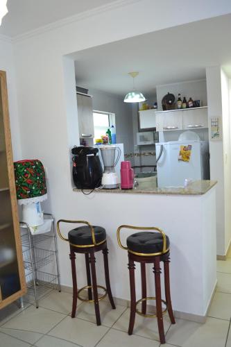 una cocina con 2 taburetes y una barra en Apartamento de dois quartos em Ponta Negra - Excelente Localização, en Natal
