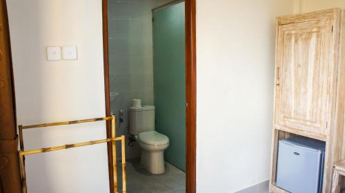 uma casa de banho com um WC e uma parede verde em Dana Homestay em Canggu