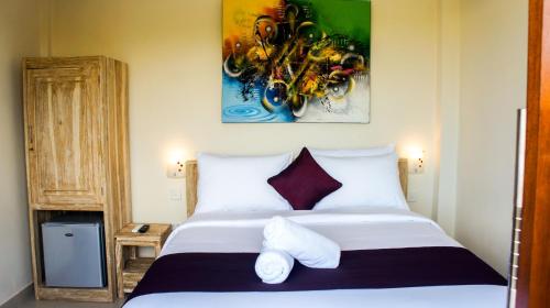a bedroom with a large white bed and a painting on the wall at Dana Homestay in Canggu
