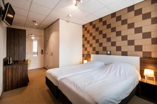 a bedroom with a bed and a checkerboard wall at Sporthotel Bruurs in Baarle-Nassau