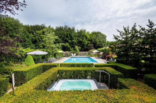 a swimming pool in a garden with bushes at Sporthotel Bruurs in Baarle-Nassau