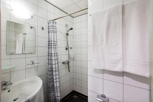 baño blanco con ducha y lavamanos en Sporthotel Bruurs en Baarle-Nassau