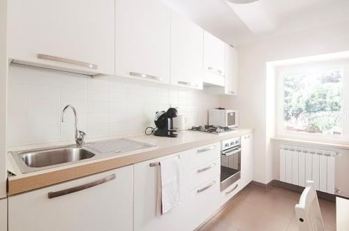 a kitchen with white cabinets and a sink and a window at Casa Del Cavaliere in La Spezia