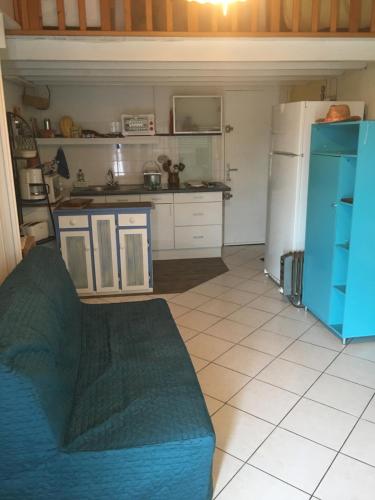 a kitchen with a blue couch and a refrigerator at Les balcons de la Medtirrannée front de mer in Narbonne-Plage