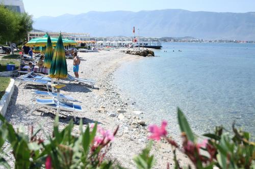 a beach with chairs and umbrellas and the water at Hotel Lepenica in Vlorë