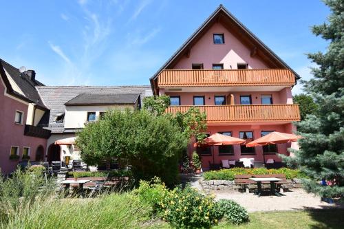 a hotel with tables and umbrellas in front of it at Landhotel Steigerwaldhaus in Burghaslach