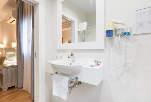 a white bathroom with a sink and a mirror at California in Málaga