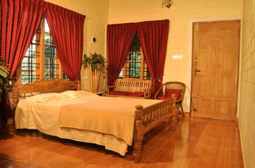a bedroom with a large bed with red curtains at The Four Seasons in Kalpetta