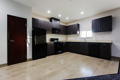 a kitchen with black cabinets and a wooden floor at Palacio Royale Inn Boutique Katy in Katy