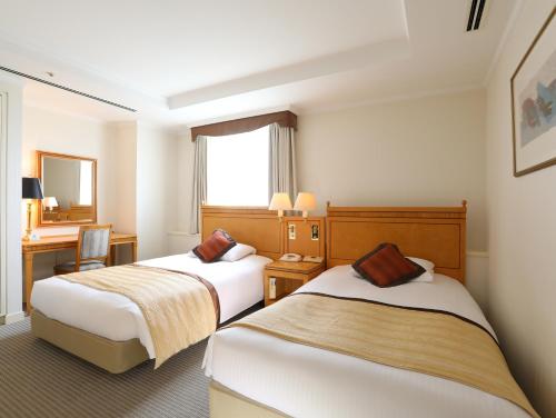 Pokój hotelowy z 2 łóżkami i biurkiem w obiekcie Wishton Hotel Yukari w mieście Sakura