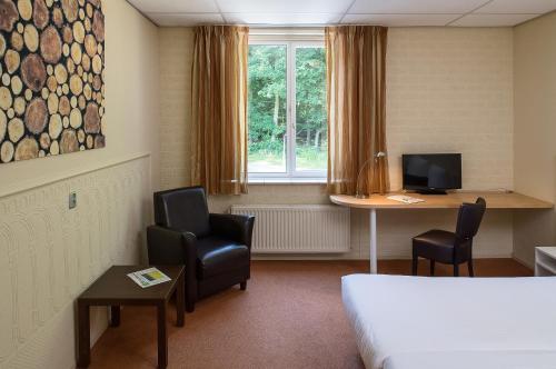 een hotelkamer met een bed en een bureau met stoelen bij Parkhotel De Bosrand in Ede