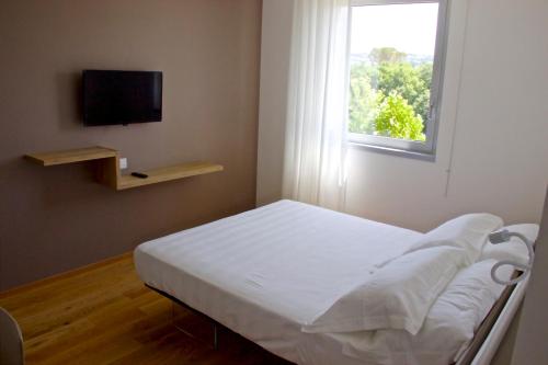 a white bed in a room with a window at Chiaroscuro in Belforte del Chienti