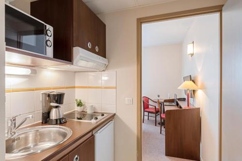 a kitchen with a sink and a table in a room at Appart'City Classic Montelimar in Montélimar