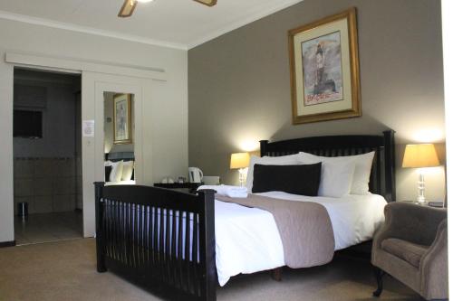 a bedroom with a large bed and a chair at Fin and Feather Guest Lodge in Boksburg