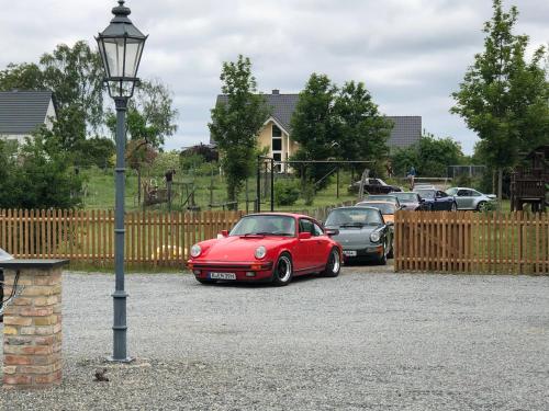 a red car parked in a parking lot next to a fence at Hotel Zur Linde Dein Self Check In in Michendorf