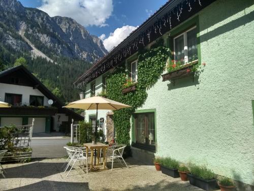 ein grünes Gebäude mit einem Tisch und einem Sonnenschirm in der Unterkunft Gasthof Zum Lugauer in Radmer an der Hasel