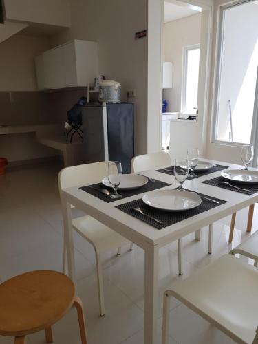 a white table with four chairs and wine glasses on it at Redwood Residence in Pangkalpinang