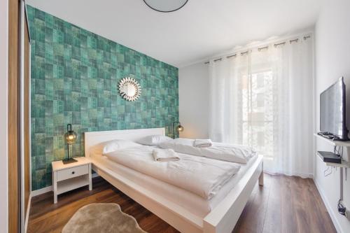 - une chambre avec un lit et un mur vert dans l'établissement Apartamenty Sun & Snow Aura II, à Gdańsk