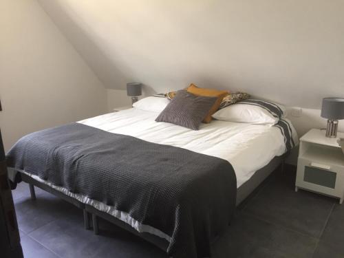 une chambre avec un lit avec des draps blancs et des oreillers dans l'établissement Venasque Vue Apartment, à Saint-Mamet