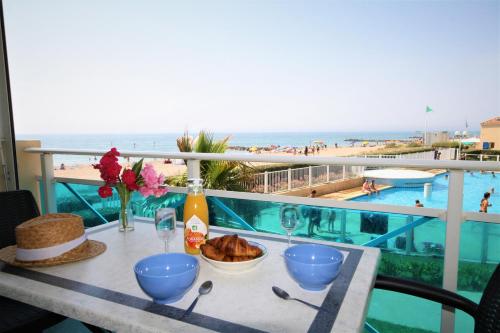 une table avec un bol de pain et des verres à vin sur un balcon dans l'établissement Résidence la Voile Blanche 4, à Frontignan