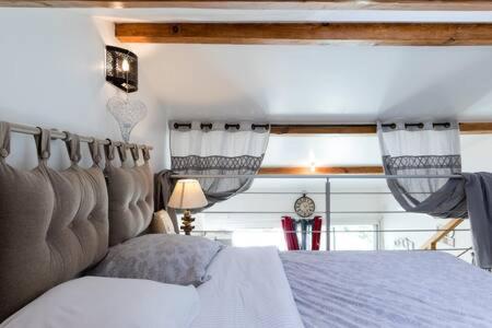 a bedroom with a bed with curtains and a clock at PETIT COIN DE CHARME in Seyresse