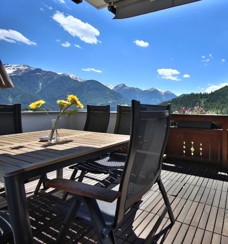 a wooden table and chairs on a deck with mountains at Appartements Haus JÖRG in Serfaus