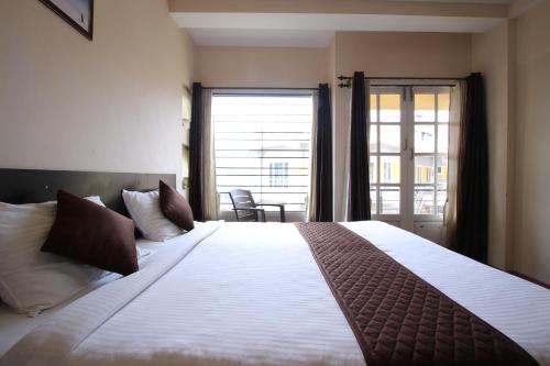 a bedroom with a large bed with a large window at The Hill Side in Ooty