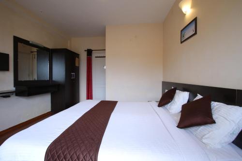a bedroom with a large bed with white sheets at The Hill Side in Ooty