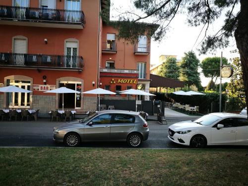 two cars parked in a parking lot in front of a building at Motel Villaggio in Imola