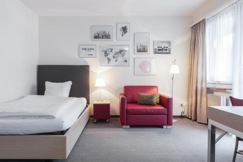 a hotel room with a bed and a red chair at EMA House Serviced Apartments Seefeld in Zürich
