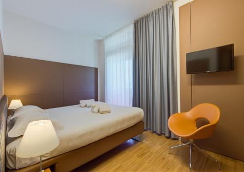 a bedroom with a bed and a chair and a television at Camplus Bononia Casa per Ferie in Bologna