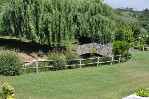 a stone bridge over a field with a fence and grass at Quinta da Serrana in Ourém