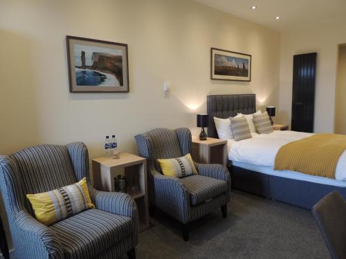 a hotel room with a bed and two chairs at Heatherlea in Kirkwall