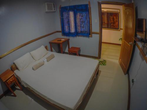 Roxas的住宿－大洋莊園賓館，卧室配有一张白色大床