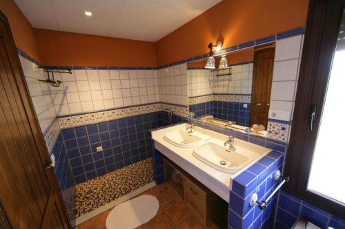 W łazience znajduje się umywalka oraz ściany wyłożone niebiesko-białymi kafelkami. w obiekcie Casa Rural la Serrana w mieście La Carlota
