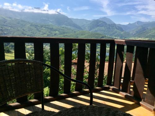 a chair sitting on a balcony with a view of mountains at La Xamoca Apartamentos Rurales in Campiellos