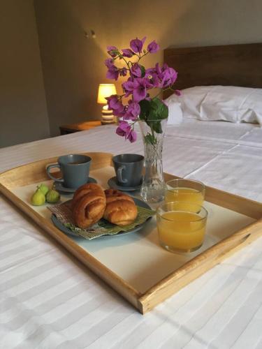 a tray with pastries and drinks and flowers on a bed at Bed & Breakfast Kurtic in Supetar